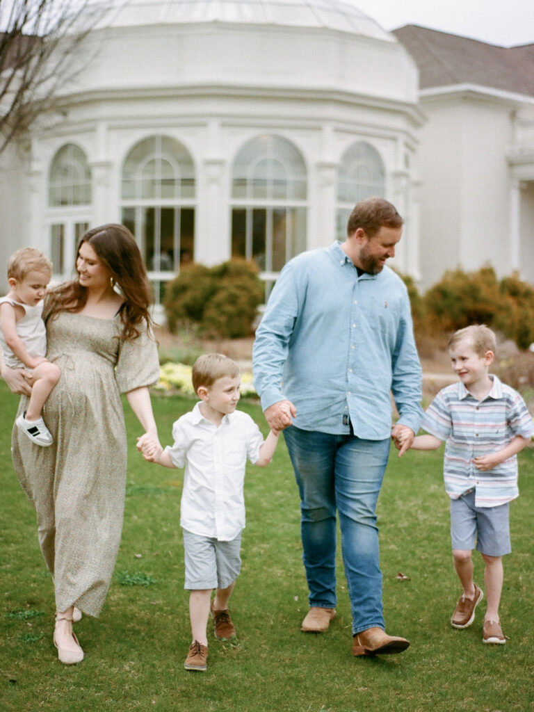 A family walking through the Huntsville Botanical Garden at their maternity photo session.