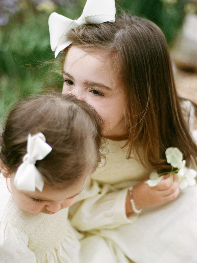 A toddler kisses her baby sister's head