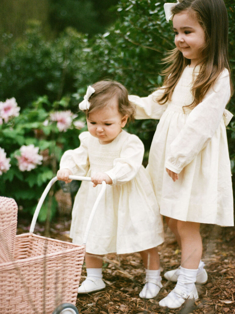 Two toddlers in yellow dresses pose together during their Huntsville Botanical Garden family photos.