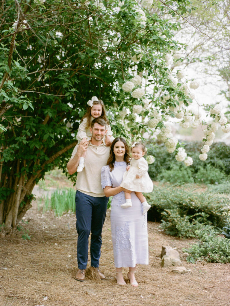 Parents pose with their two toddlers, all smiling at the camera, while taking their Huntsville Botanical Garden family photos with Fauna & Film.