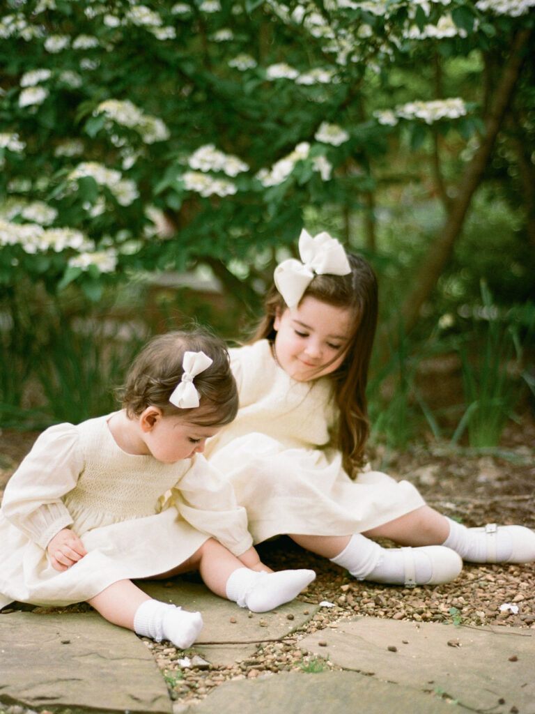Two toddlers in yellow dresses pose together during their Huntsville Botanical Garden family photos.