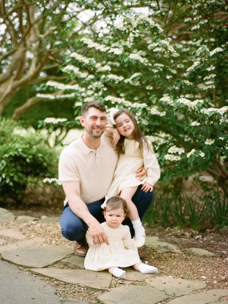 A father poses with his two young daughters at their Huntsville Botanical Garden family photo session with Fauna & Film