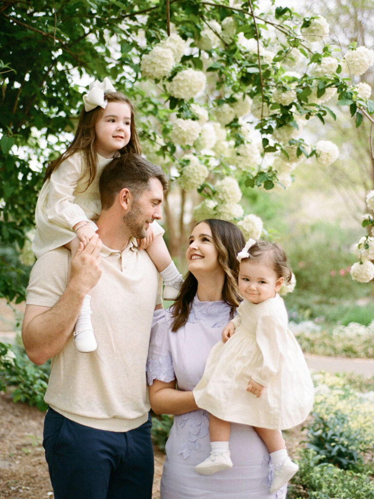 Parents pose with their two toddlers, smiling at each other, while taking their Huntsville Botanical Garden family photos with Fauna & Film.