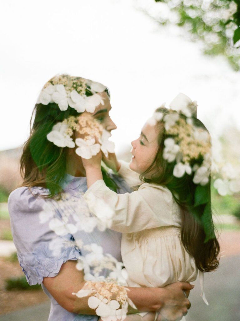 A double exposure of flowers and a mother holding her young daughter while they both laugh at their Huntsville Botanical Garden family photoshoot 