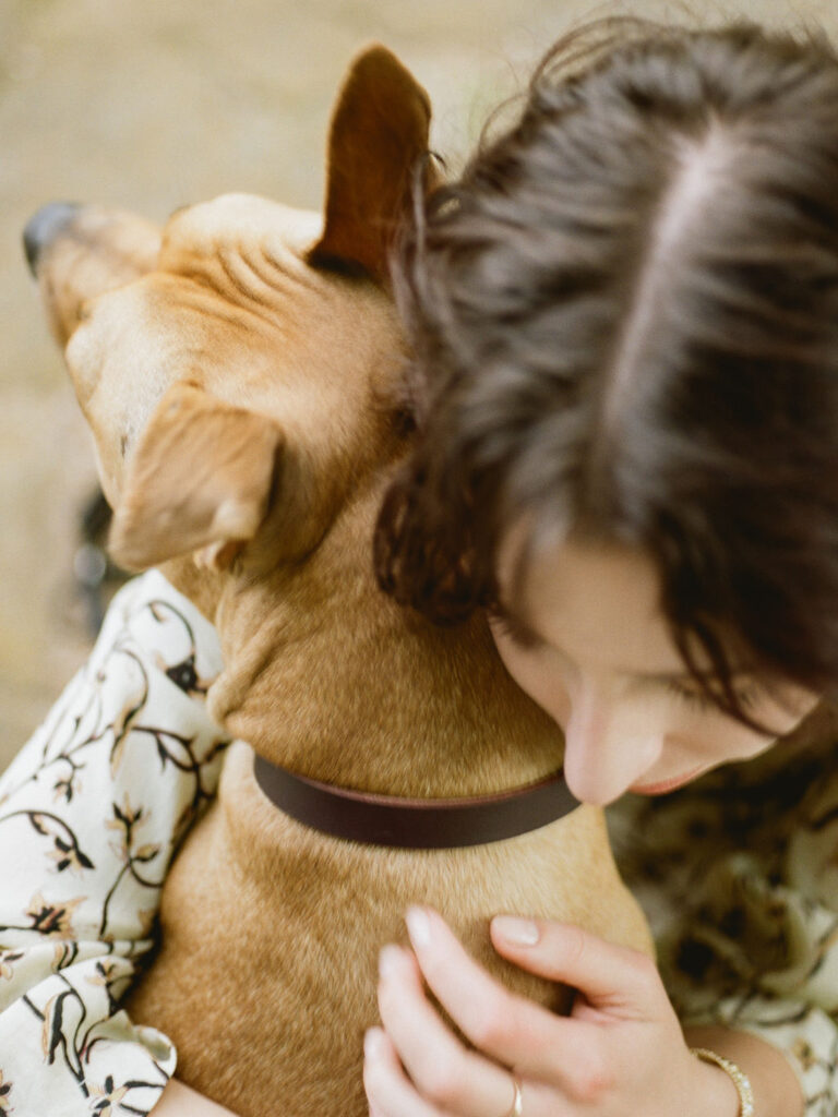 A closeup of a dog resting his head on his owner's shoulder while she embraces him during their session with Huntsville pet photographer Fauna & Film