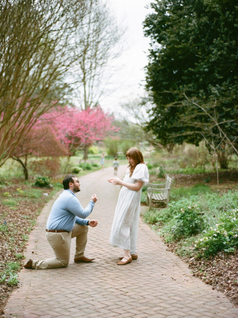 A man on one knee and a woman smiling and laughing during their Huntsville Botanical Garden proposal