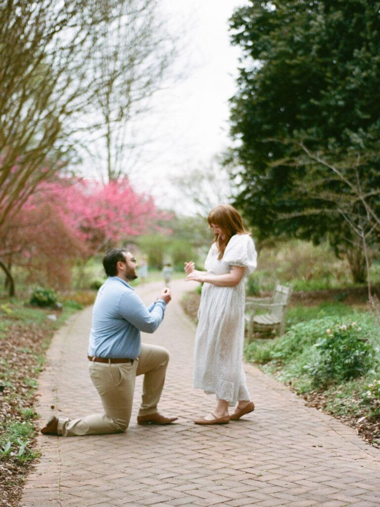 A man on one knee and a woman smiling and laughing during their Huntsville Botanical Garden proposal