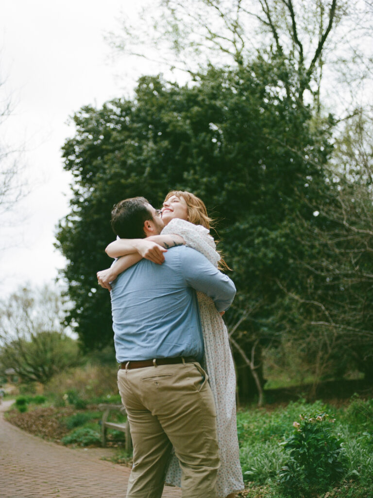 A couple embracing and laughing at their Huntsville Botanical Garden Proposal