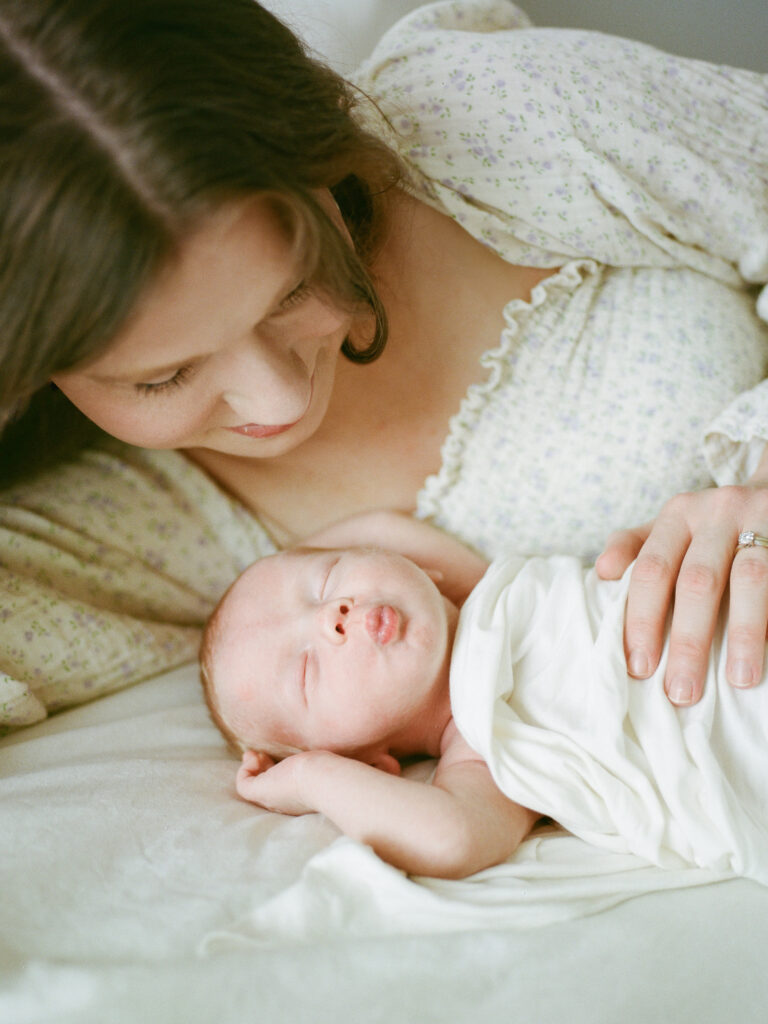 A mother lies on a bed gazing at her baby son during their session with Huntsville maternity and newborn photographer Fauna & Film