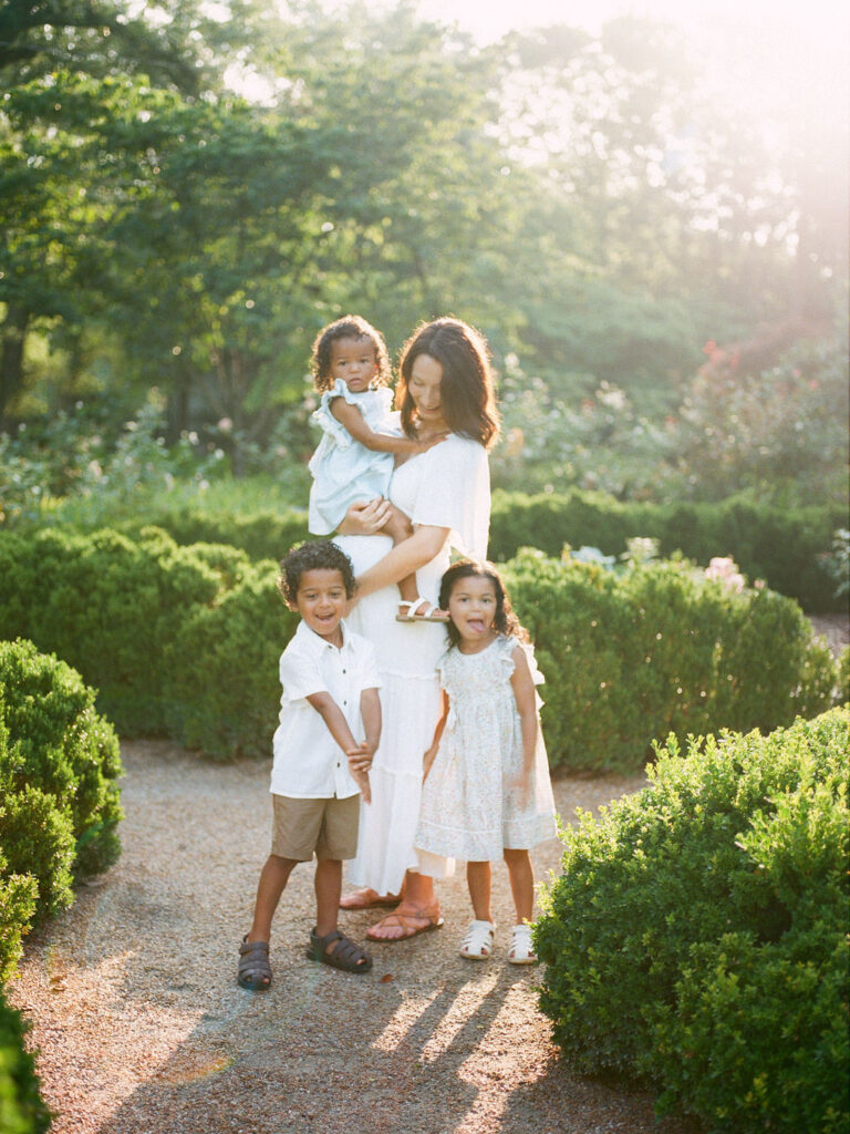 A mother, holding her two-year-old daughter, poses with her twin four-year-olds at Delano Park in Decatur, AL