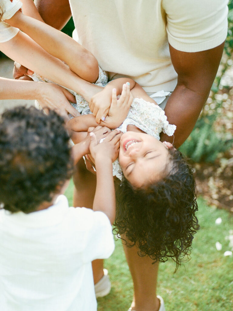 family tickles daughter in rose garden during maternity session by alabama photographer fauna & film