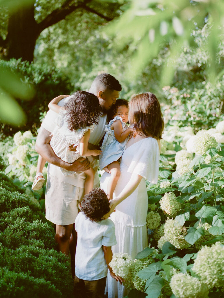 family embraces surrounded by hydrangeas in delano park rose garden by alabama family photographer fauna & film