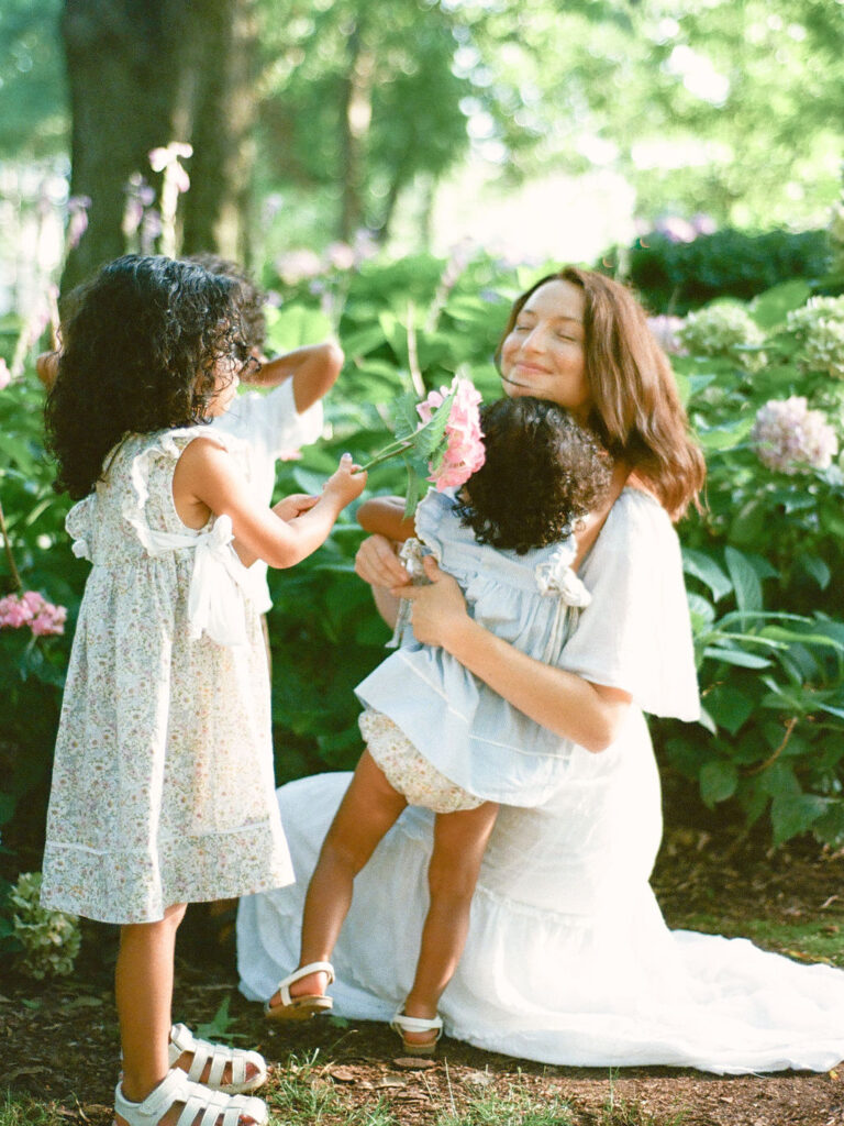mother and daughters smell hydrangeas in delano park rose garden by fauna & film