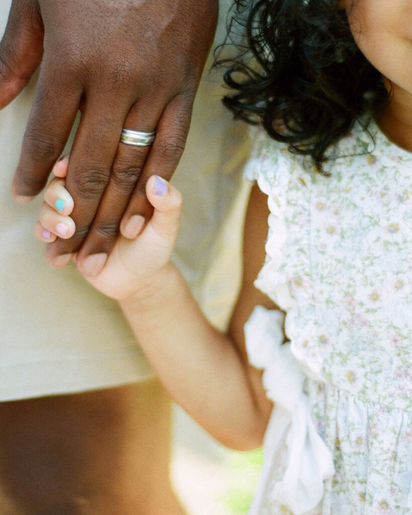 Closeup of a small child holding her dad's hand at their Delano Park family and maternity photos