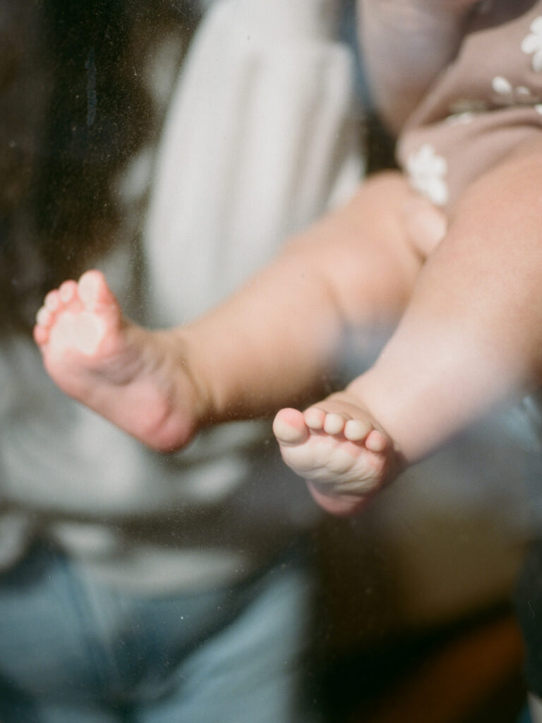 A closeup of a baby's toes pressed against a window