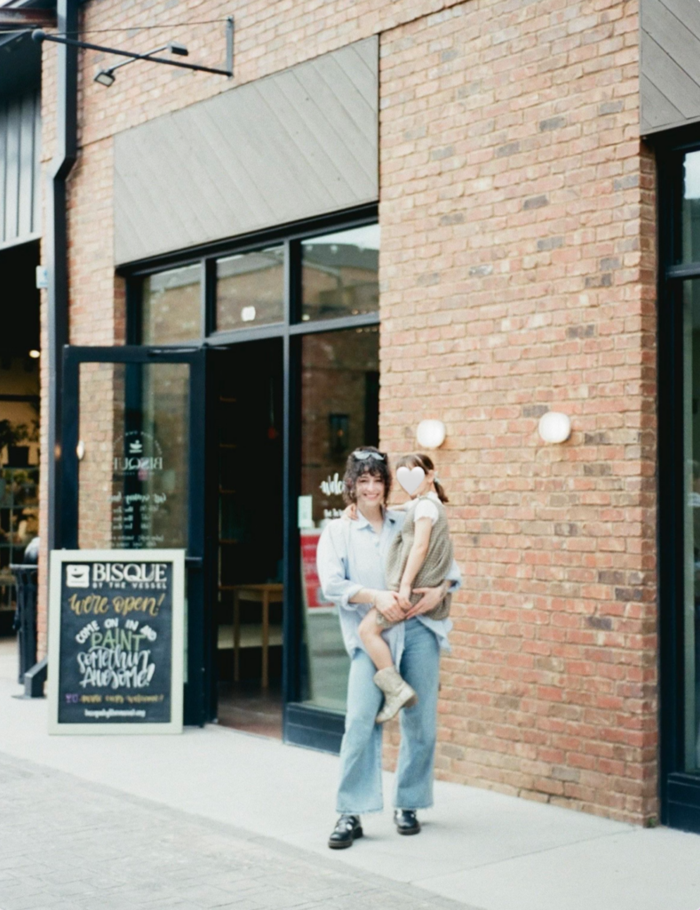 A mom and daughter posing in front of paint-your-own pottery studio Bisque by the Vessel in Huntsville AL