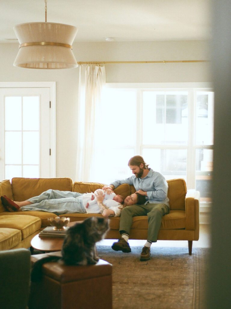 in the background, a family poses together on a couch while a cat sits in the foreground