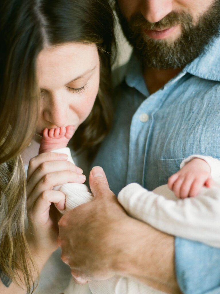a mother kisses her baby during newborn photos at home