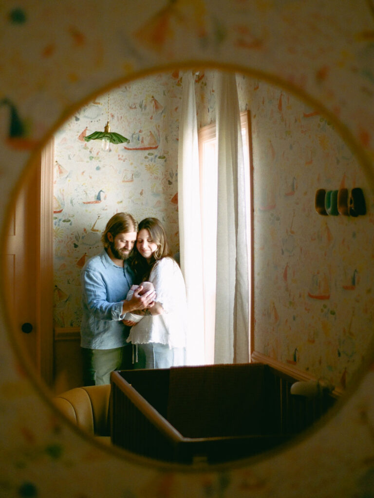 a reflection of a man and a woman looking at their baby newborn photos at home