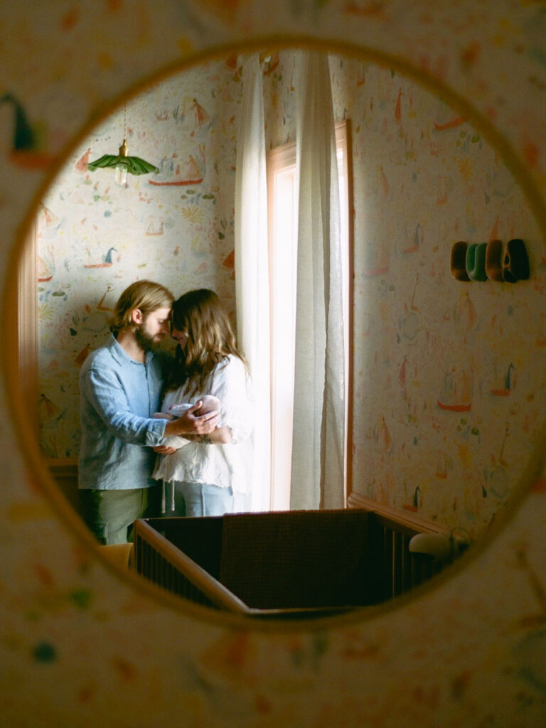 a film photo of a couple posing with their baby while taking newborn photos at home