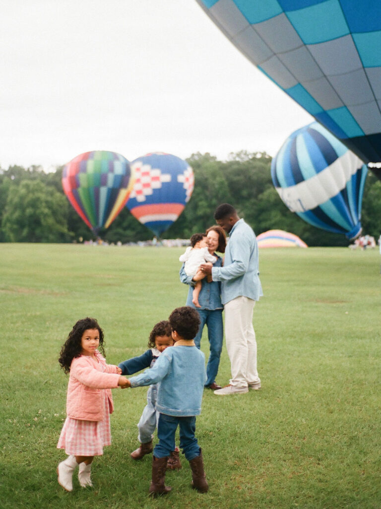 children play together while parents share embrace at hot air balloon festival at point mallard park