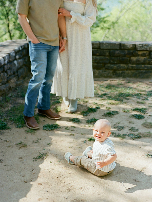 couple holds hands behind smiling baby at monte sano state park photo session